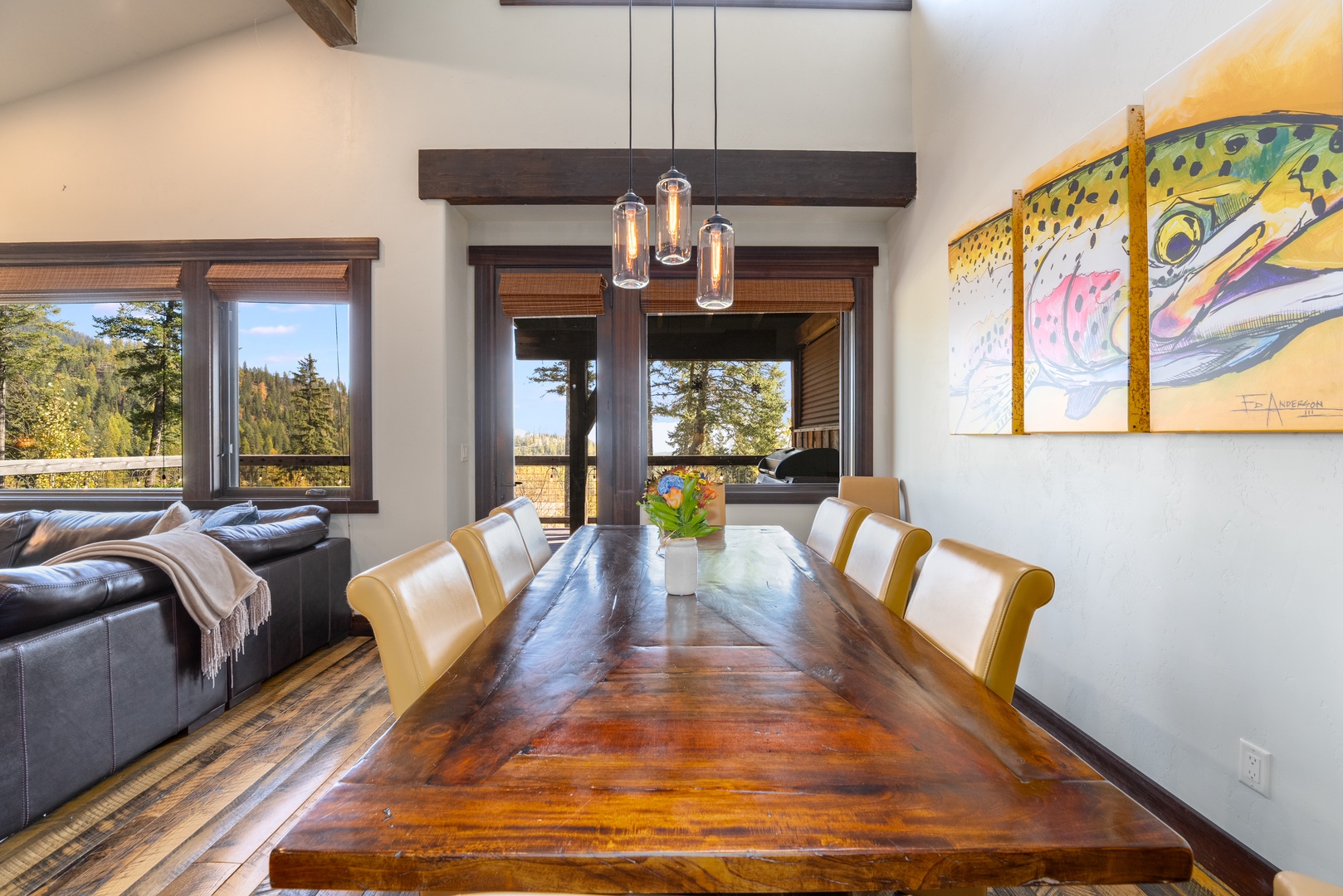 Gather around this stunning live-edge dining table where meals become memories. Floor-to-ceiling windows frame forest views, while modern pendant lights cast a warm glow over your evenings together.