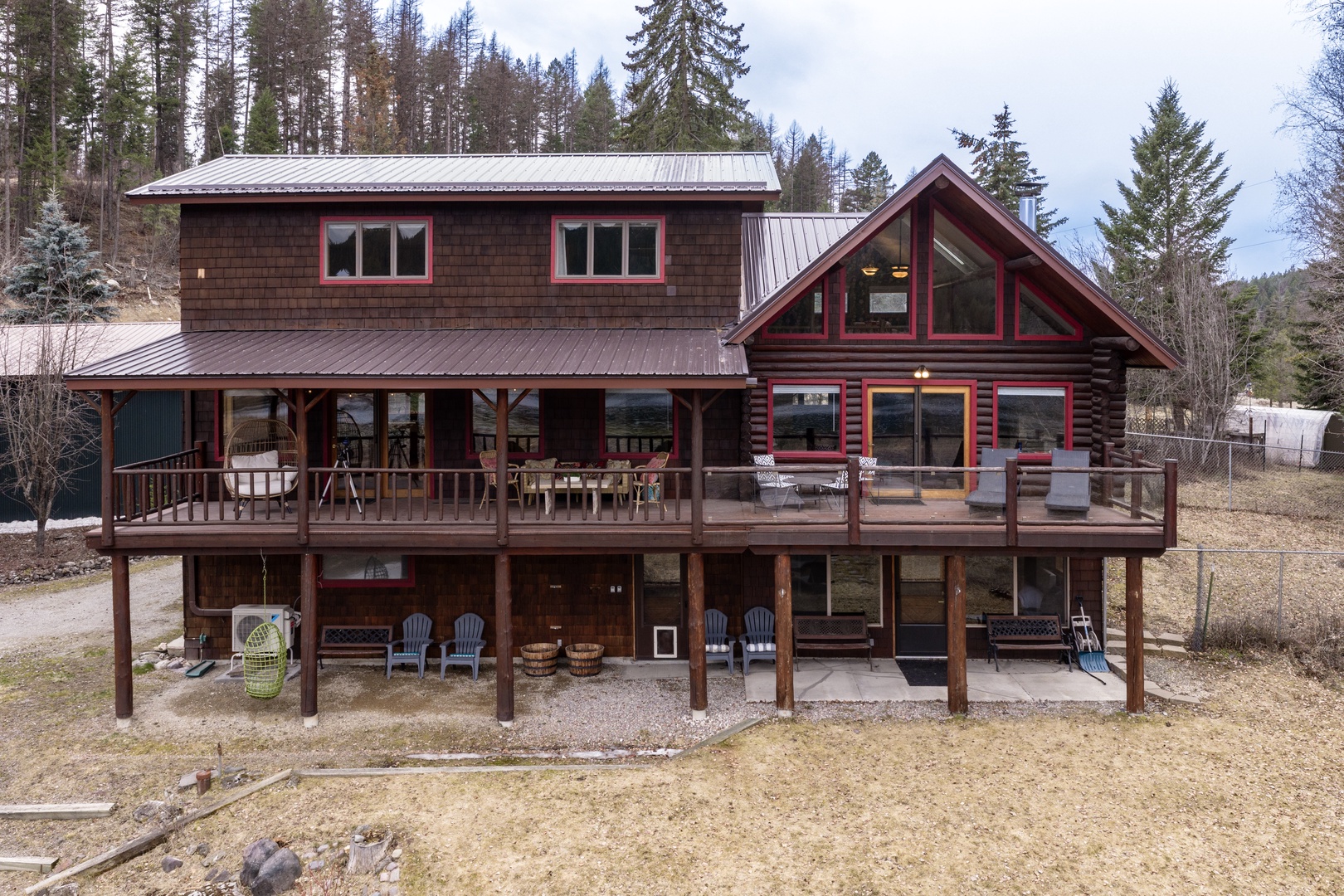 Charming mountain lodge with multi-level deck sits nestled among towering pines, offering a peaceful forest retreat.