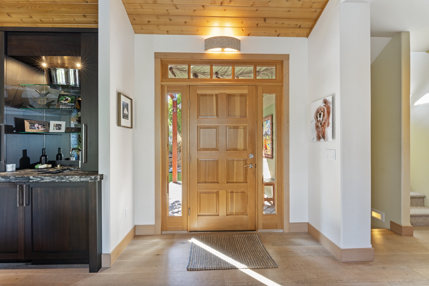 Bright natural light streams through the elegant entry, welcoming you into a warm, open space with soaring wood ceilings and modern mountain charm.