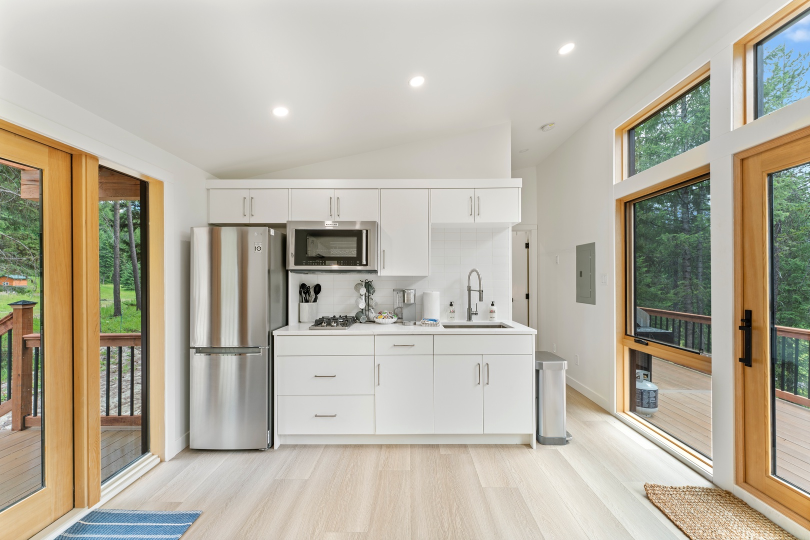 Your bright, modern kitchen features everything you need, surrounded by gorgeous forest views through floor-to-ceiling windows.