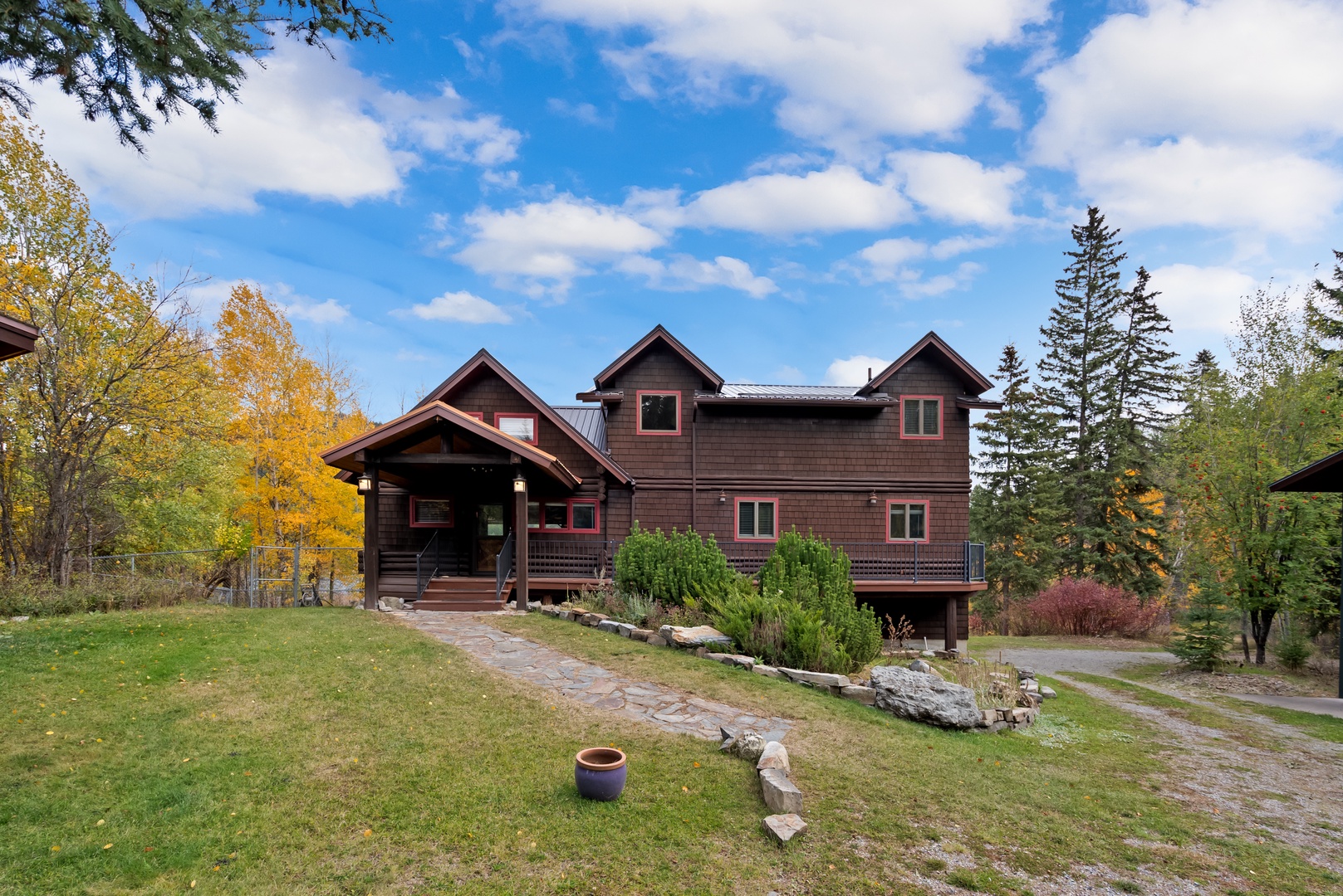Charming mountain lodge surrounded by vibrant autumn foliage and mature evergreens, creating a peaceful woodland setting.