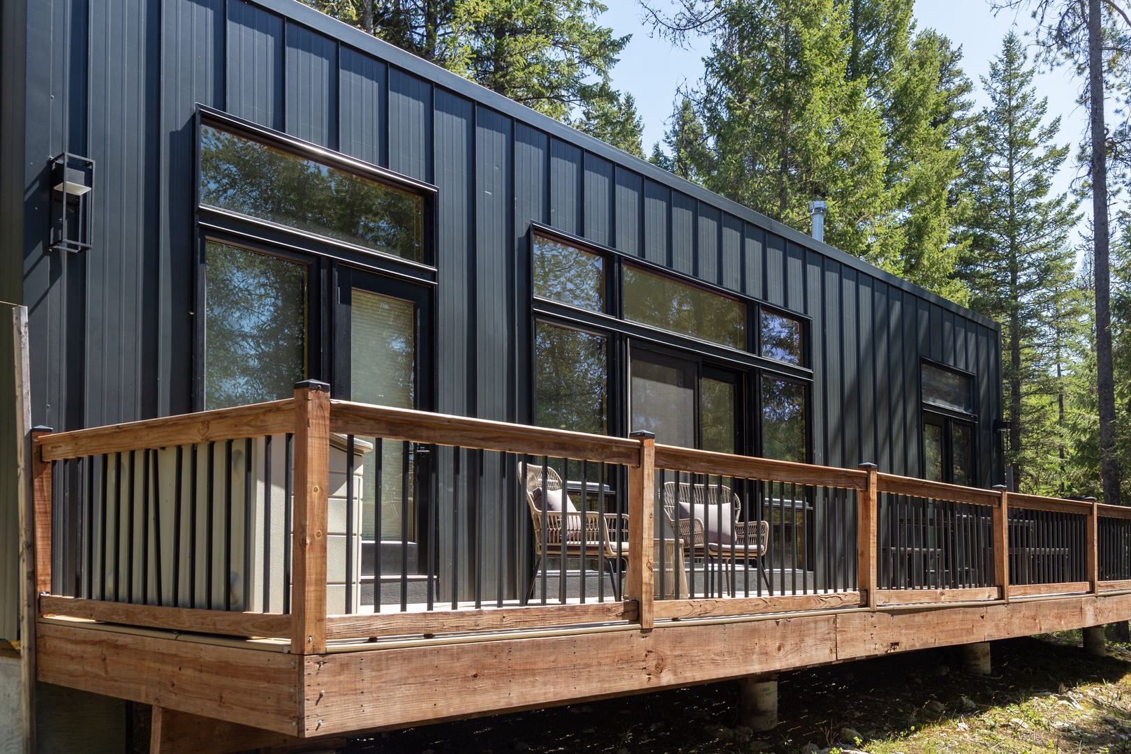 Modern vacation rental nestled in a serene forest setting, featuring a spacious wooden deck where you can unwind surrounded by towering trees and natural beauty.