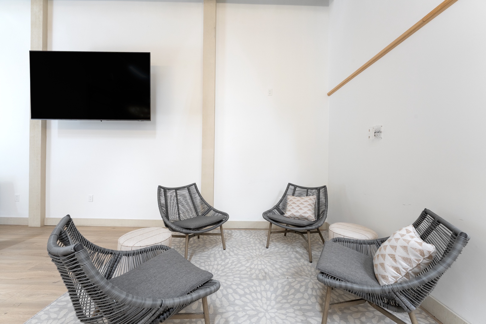 Gather here in this airy lounge with modern woven seating, a wall-mounted TV, and minimalist design—your perfect spot to unwind or socialize with your travel companions.