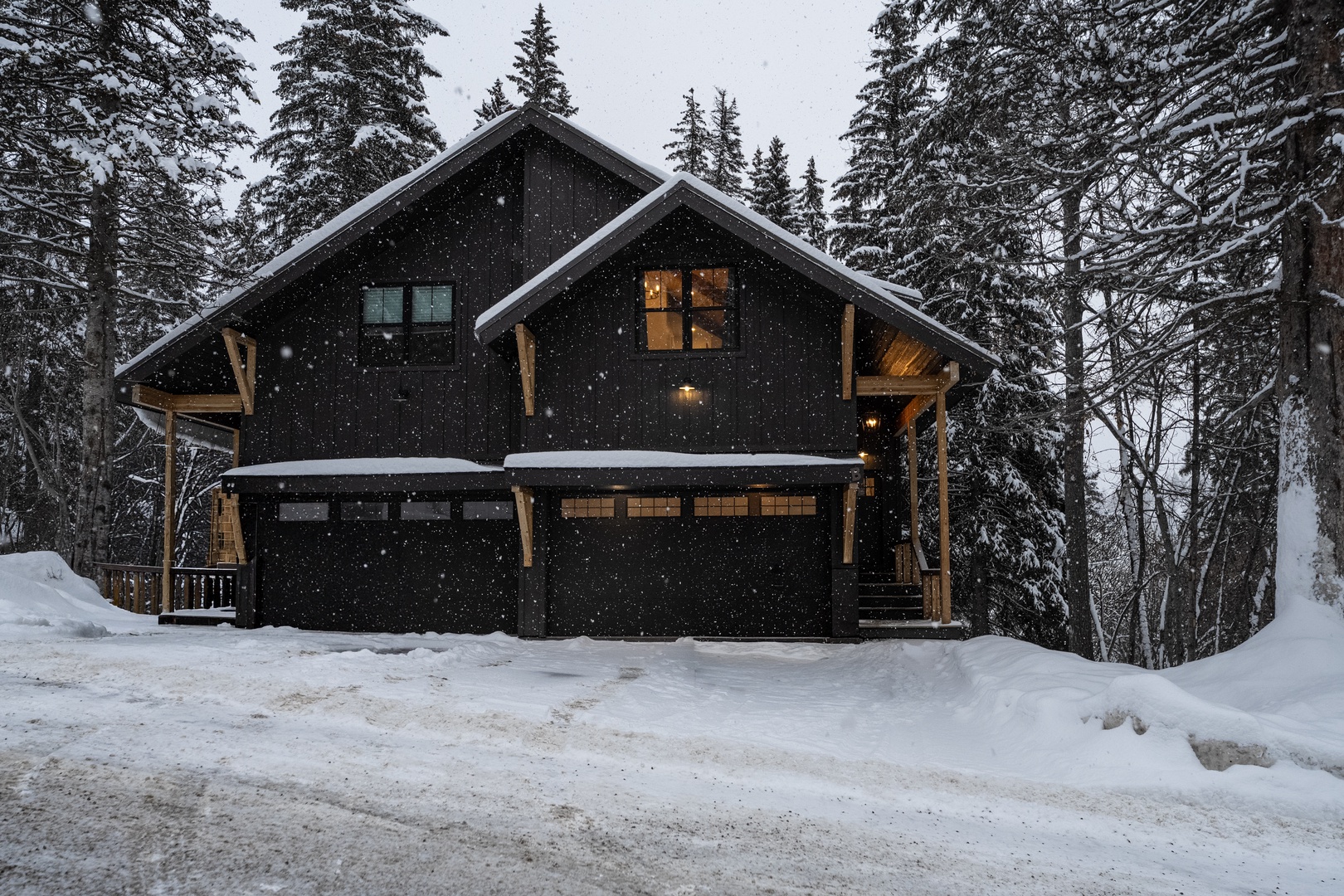 A charming mountain cabin nestled among snow-covered evergreens, offering a cozy winter retreat with warm glowing windows.