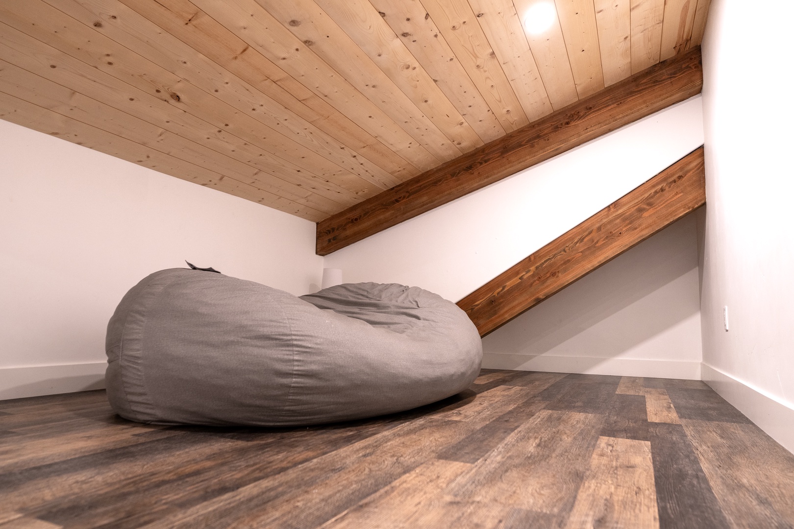 Your cozy loft hideaway features exposed wooden beams and a plush bean bag where you can unwind beneath rustic charm.
