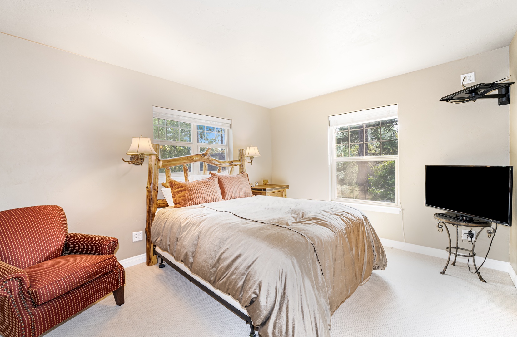 Unwind in your peaceful bedroom with its rustic log bed, plush seating, and large windows framing natural greenery.