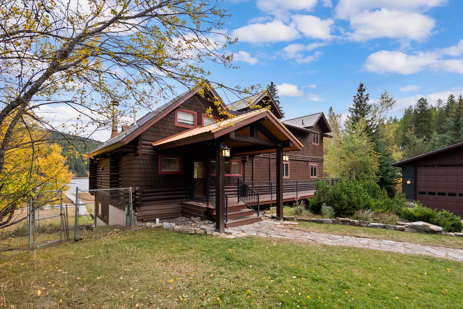 Charming log cabin surrounded by autumn foliage and nestled among tall evergreens.