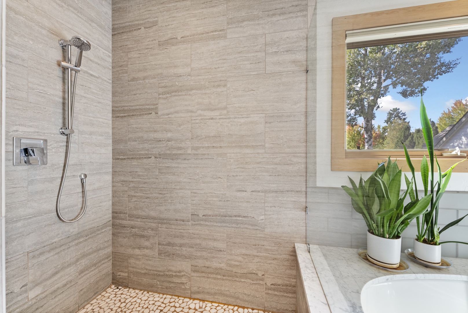 Refresh in your modern walk-in shower featuring sleek tile, a rainfall showerhead, and natural light streaming in to brighten your morning routine.