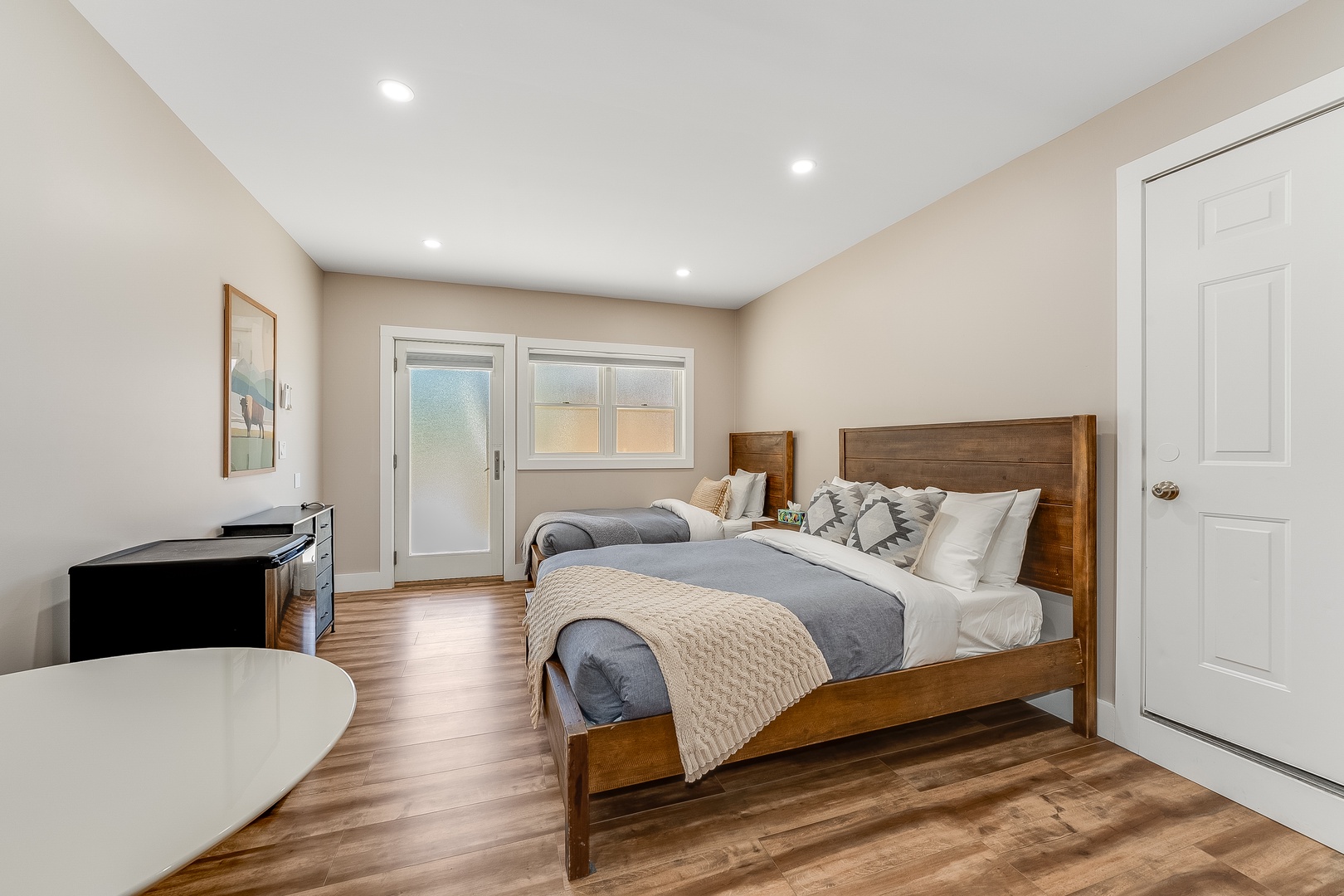 Settle into this inviting bedroom where warm wood tones and soft linens create your peaceful retreat. Twin beds provide flexible sleeping arrangements while natural light filters through glass doors.