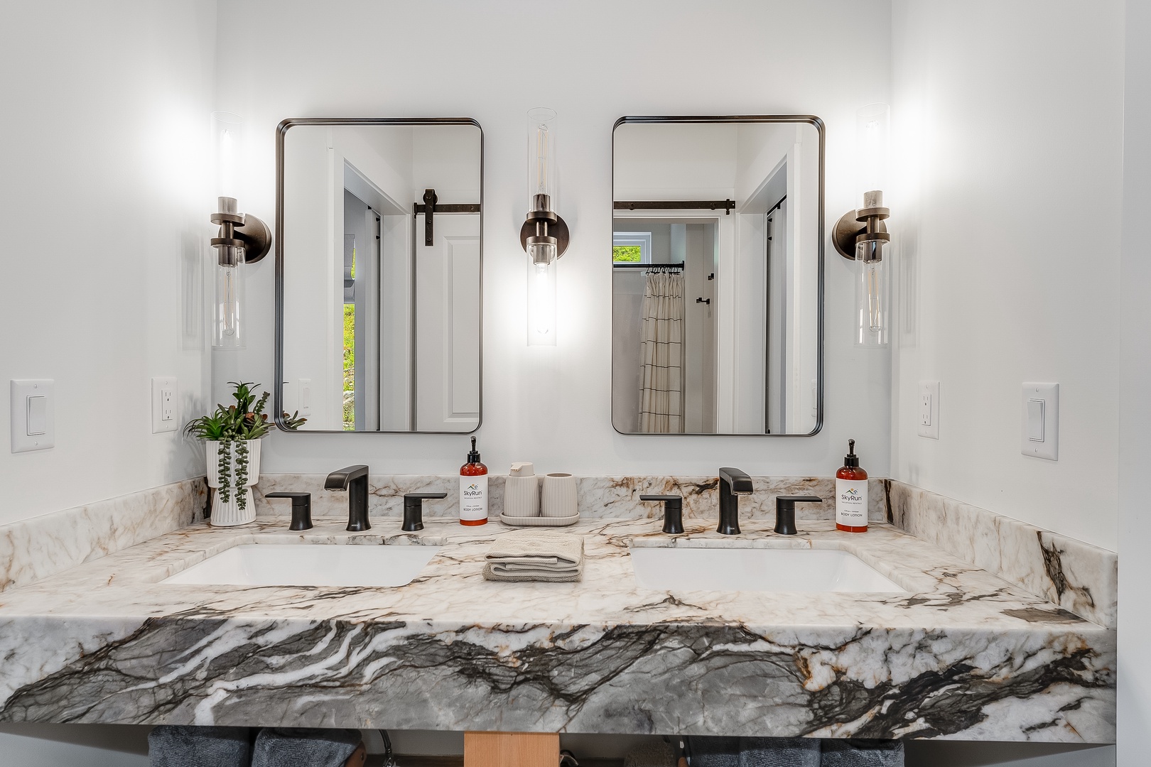 Gorgeous marble countertop spans this double vanity where your mornings begin in elegance. Modern fixtures, stylish mirrors, and designer lighting create a refined space that's all yours to enjoy.