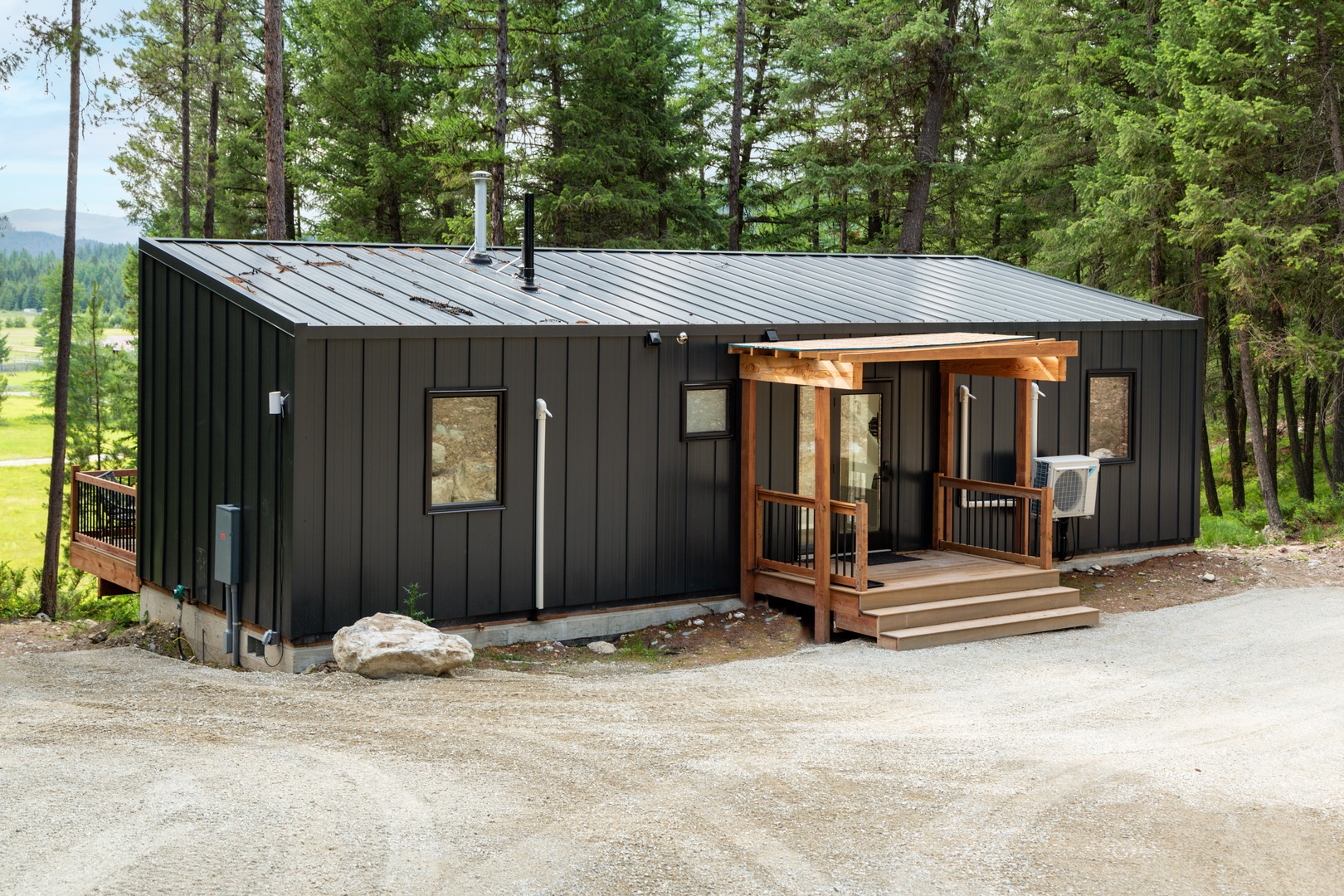 Modern cabin nestled in towering pines with warm wood accents and a welcoming covered entrance.
