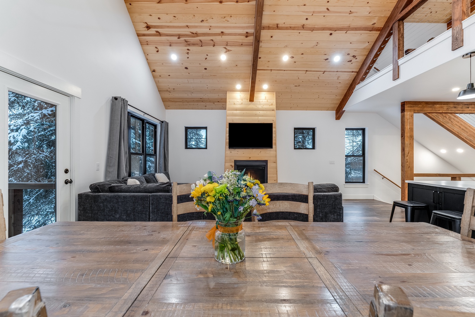 Gather around your rustic dining table while exposed beams and a crackling fireplace create the perfect mountain retreat atmosphere.