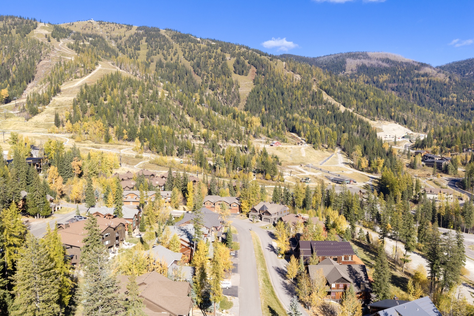 An aerial view of the mountain resort neighborhood, where autumn colors brighten the tree-covered slopes and ski runs await the coming winter season.