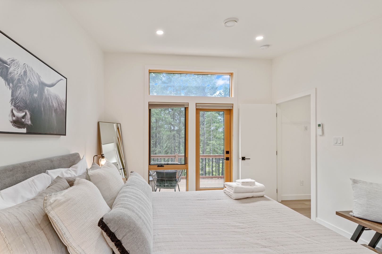 Your peaceful retreat features a plush bed, modern accents, and private balcony access framed by scenic forest views—perfect for unwinding after a day of adventure.