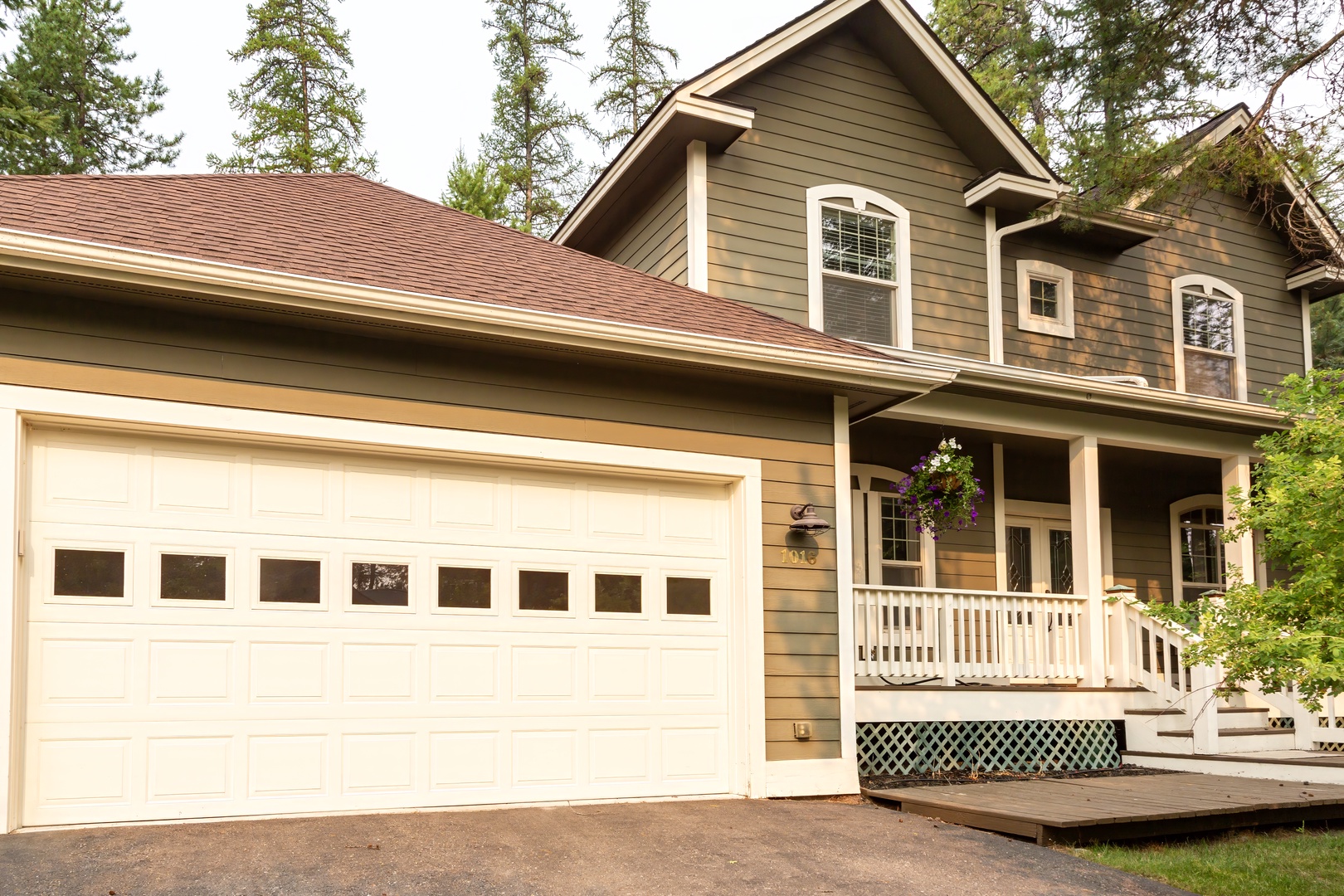 This charming home offers a welcoming covered porch and plenty of parking, nestled among tall pines for a peaceful retreat.