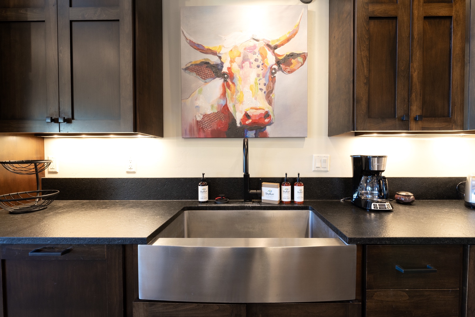 Whip up your favorite meals in this sleek, fully-equipped kitchen, complete with modern appliances and a stylish farmhouse sink. The warm under-cabinet lighting adds a cozy glow to your culinary creations.