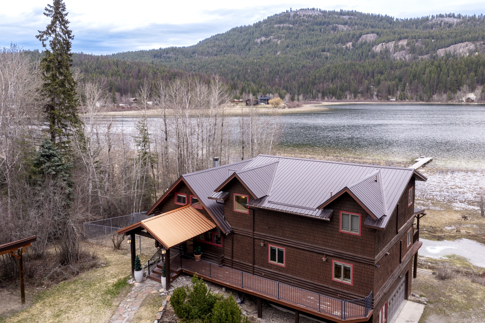 Rustic lakefront lodge nestled against forested mountains, offering panoramic views of pristine waters and natural wilderness.