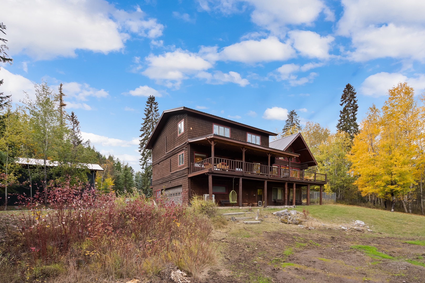 This rustic wooden retreat sits peacefully among vibrant autumn foliage and towering evergreens, offering mountain charm in a natural setting.