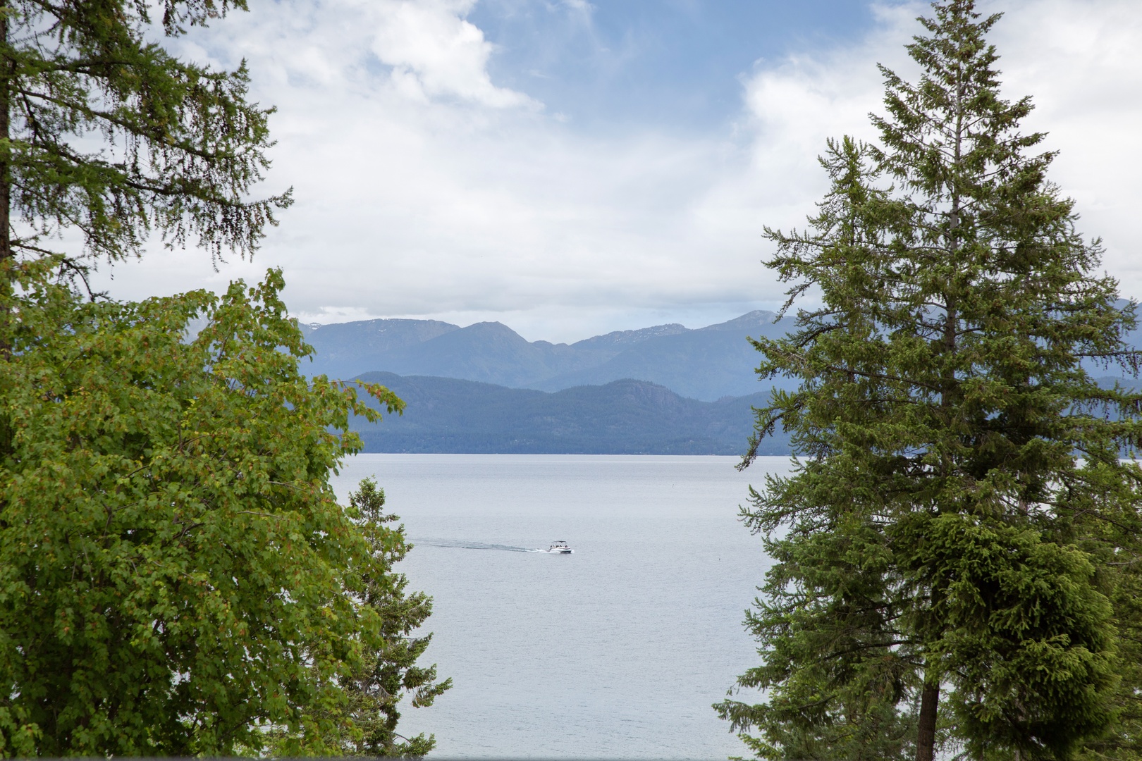 Majestic mountain peaks rise above a serene lake, framed by evergreen trees, offering a peaceful natural backdrop to the property's surroundings.