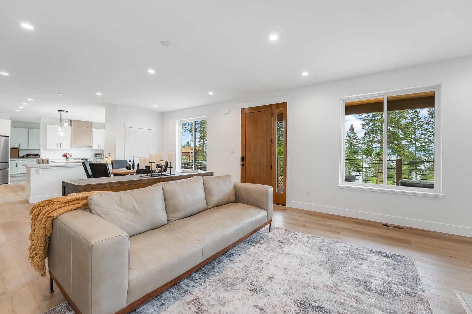 Unwind in your open-concept living space where natural light floods through expansive windows, revealing stunning tree-lined views. The sleek kitchen and cozy lounge area create the perfect backdrop for your getaway.