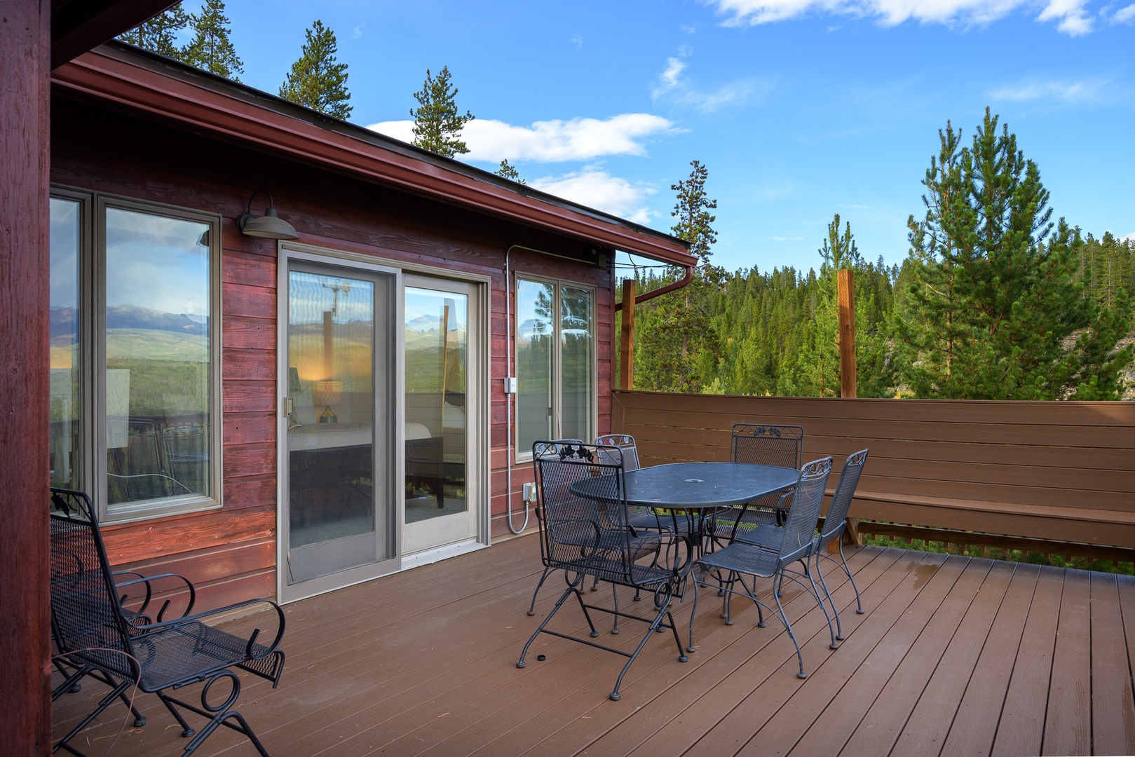Surrounded by towering pines and clear blue skies, your private deck offers a peaceful spot to gather outdoors with mountain views on the horizon.