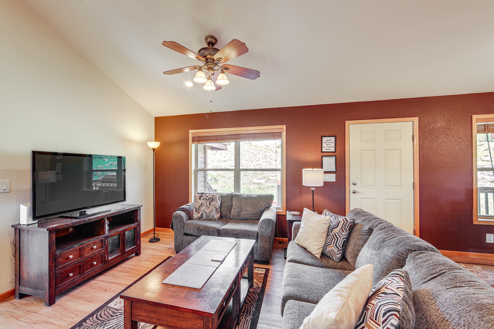 Unwind in your comfortable living room with plush gray sofas, warm wood accents, and entertainment center for cozy evenings.