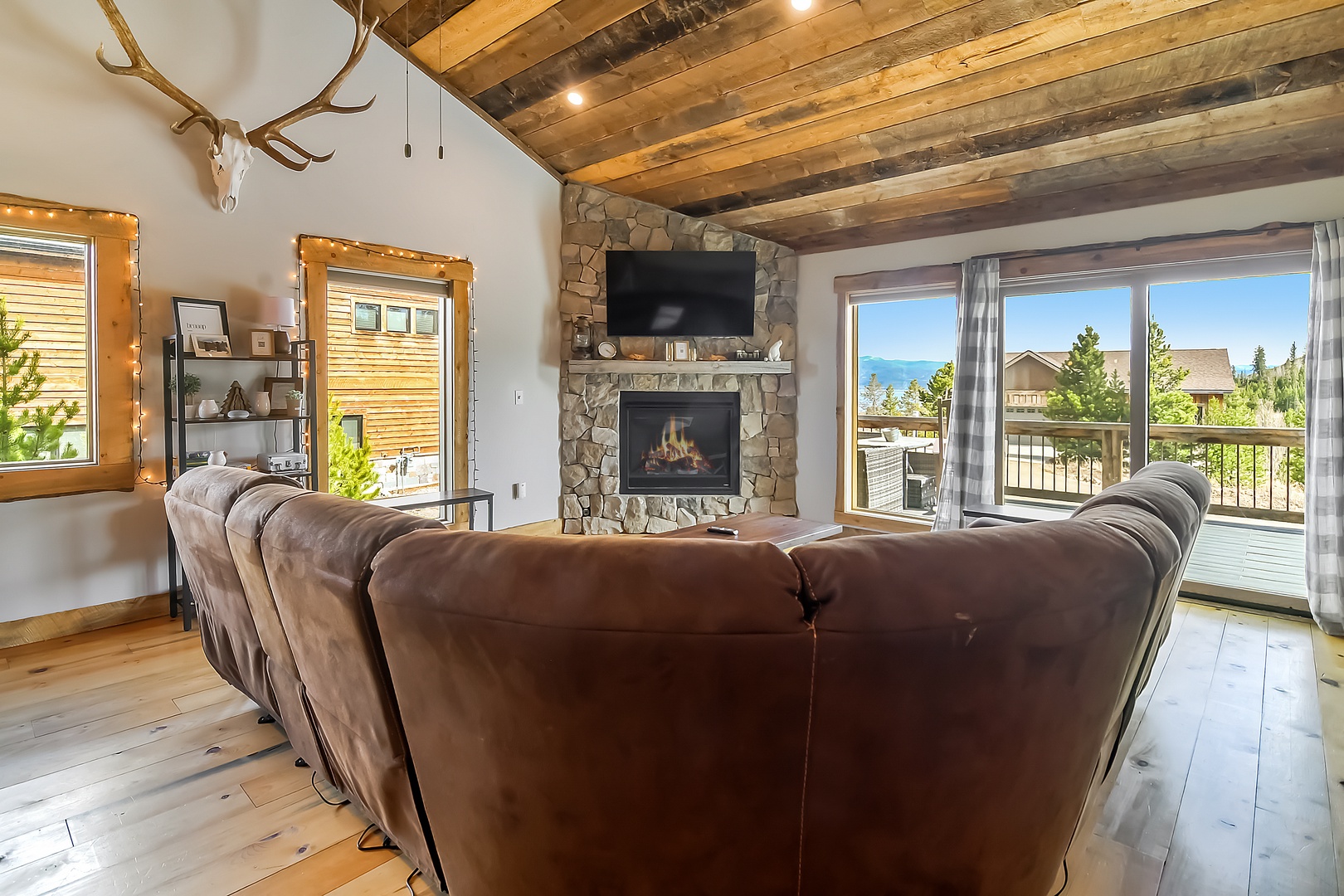 Cozy up in your spacious living room with rustic beams, stone fireplace, and lake views through floor-to-ceiling windows.
