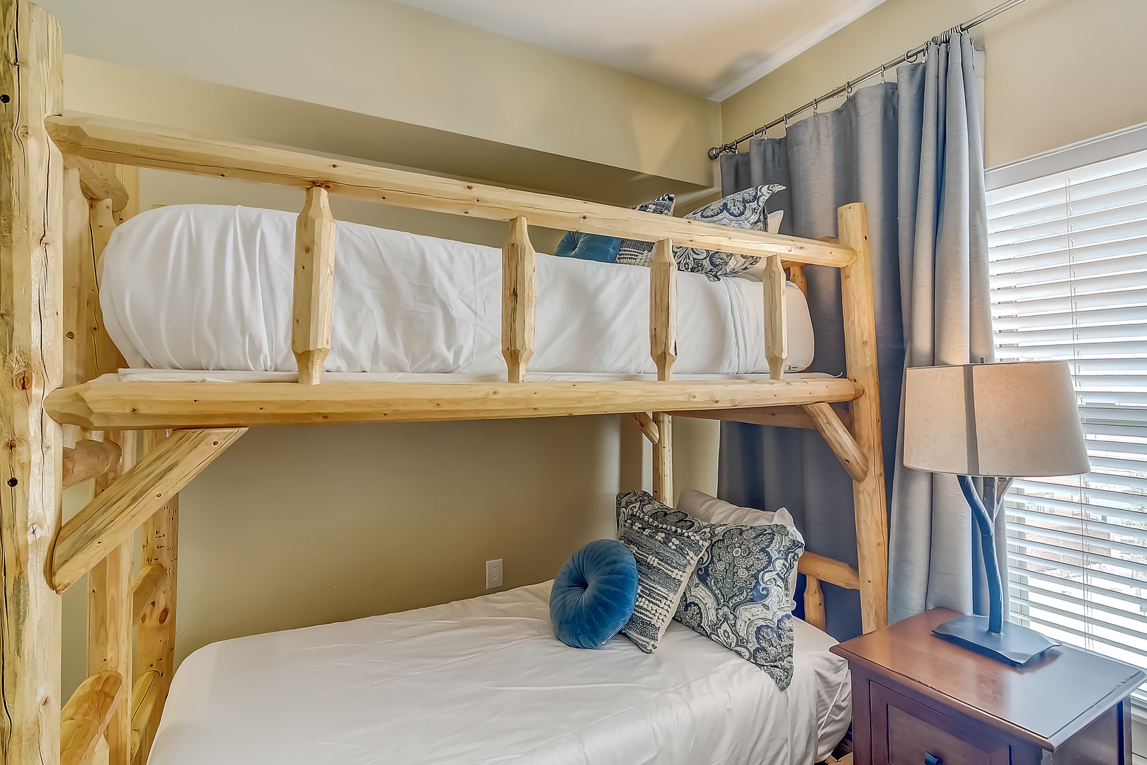 Your rustic wooden bunk bed offers cozy comfort with soft linens and decorative pillows in this welcoming bedroom.