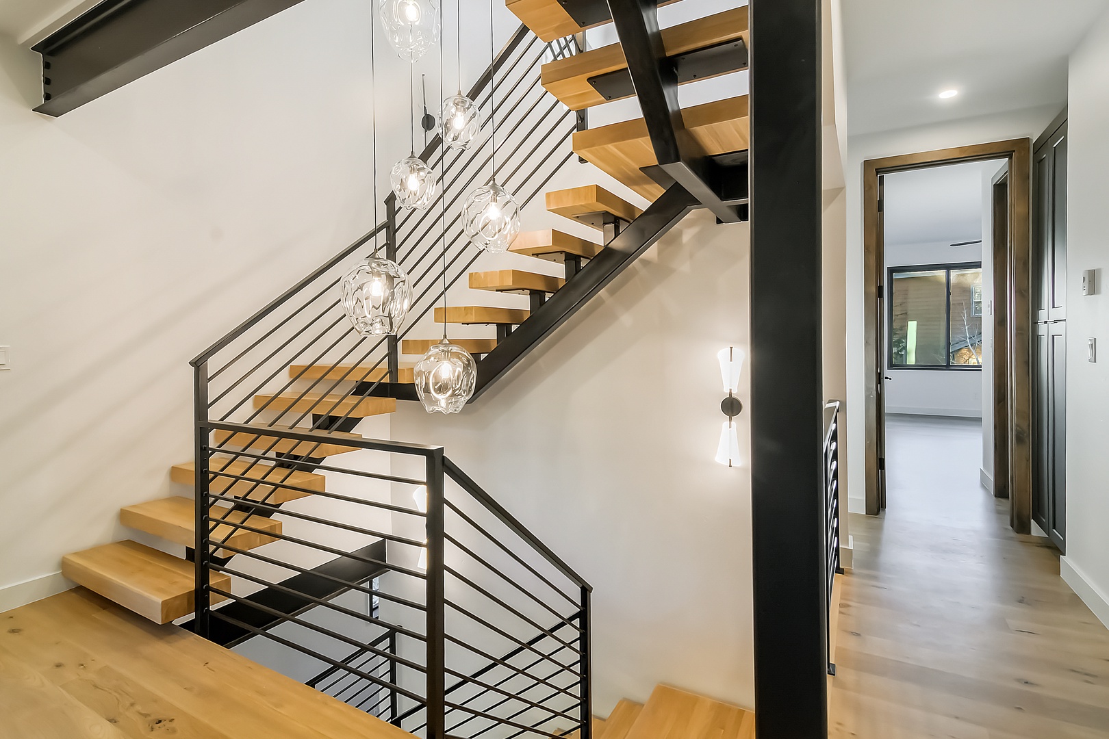 Modern staircase with warm wood treads and elegant pendant lighting creates a stunning architectural centerpiece in your stylish retreat.