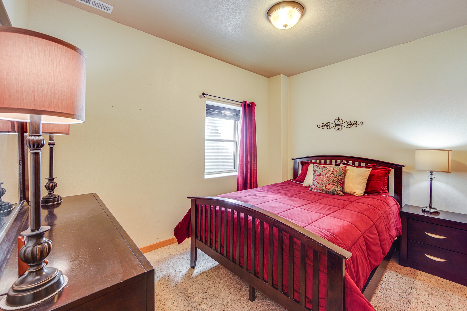 Sink into plush red bedding in your peaceful bedroom, where warm lighting and thoughtful touches create the perfect retreat after exploring.