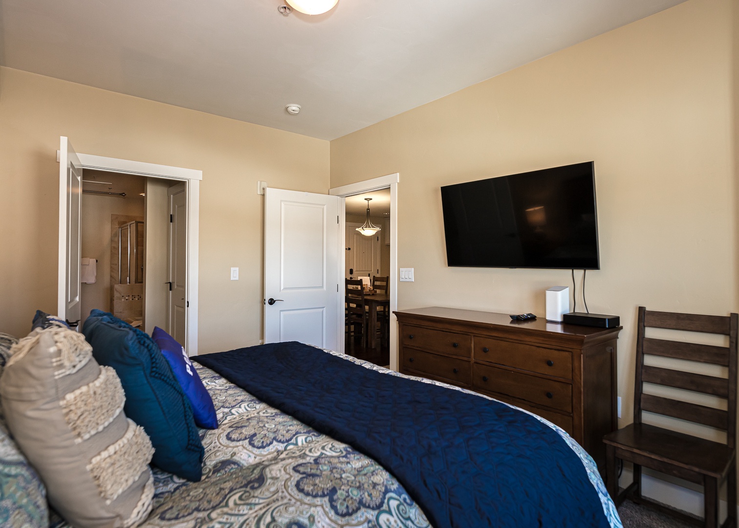 Unwind in your cozy bedroom with plush bedding, modern TV entertainment, and convenient en-suite bathroom access for ultimate comfort.