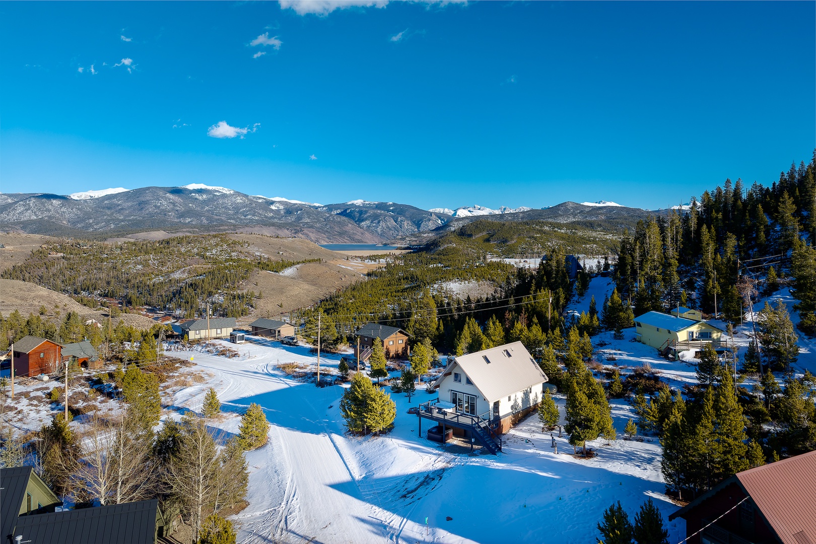 Panoramic mountain valley setting with snow-covered peaks and forested hillsides surrounding this peaceful residential area.