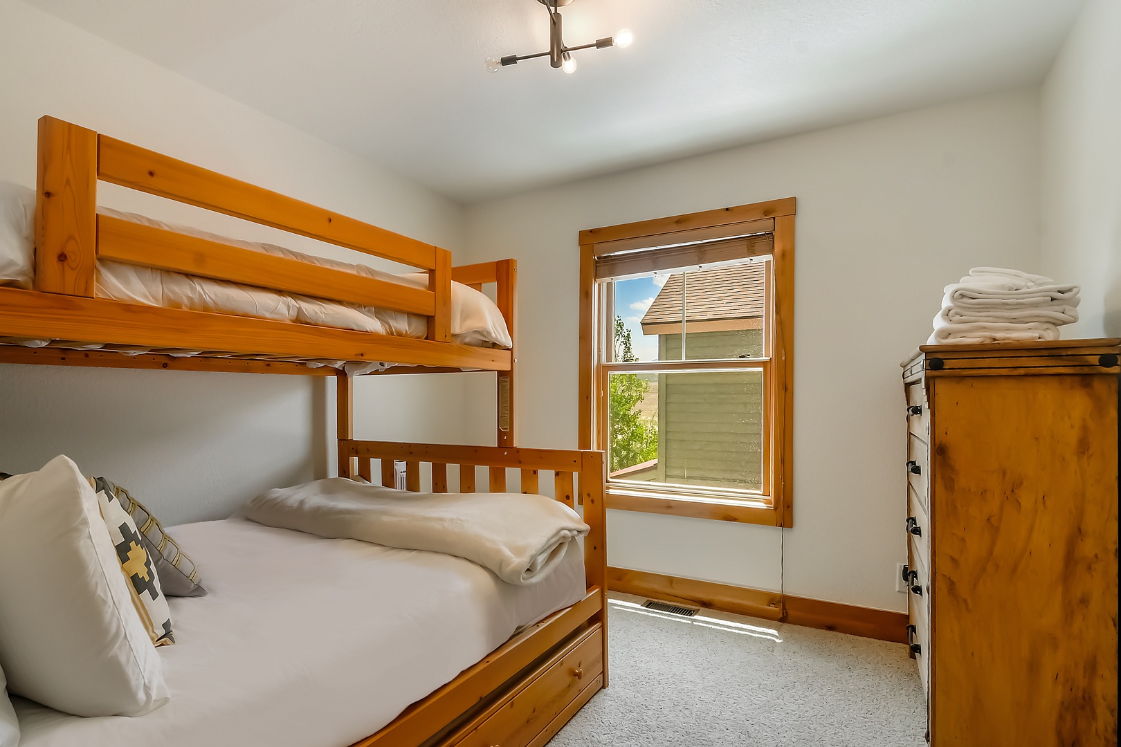 Your kids will love this cozy bunk room with warm wood tones, crisp linens, and sunlight streaming through the window—perfect for settling in after a day of adventure.