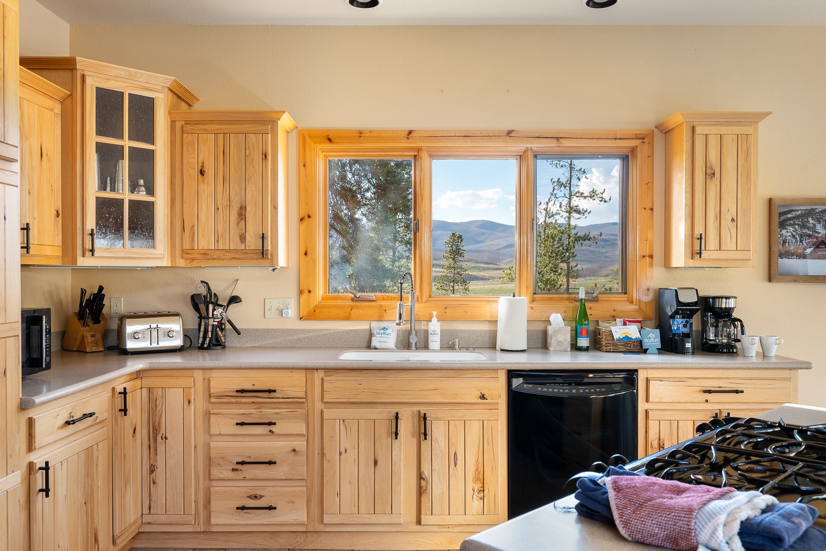 Your fully equipped kitchen features charming wood cabinetry and breathtaking mountain vistas through large windows—perfect for savoring your morning coffee while soaking in the natural beauty.