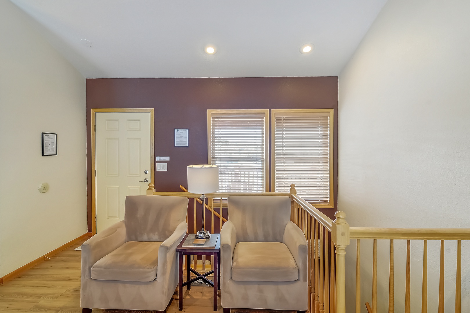 Relax in your cozy upstairs seating nook with two plush armchairs and warm lighting—perfect for morning coffee or evening conversations.