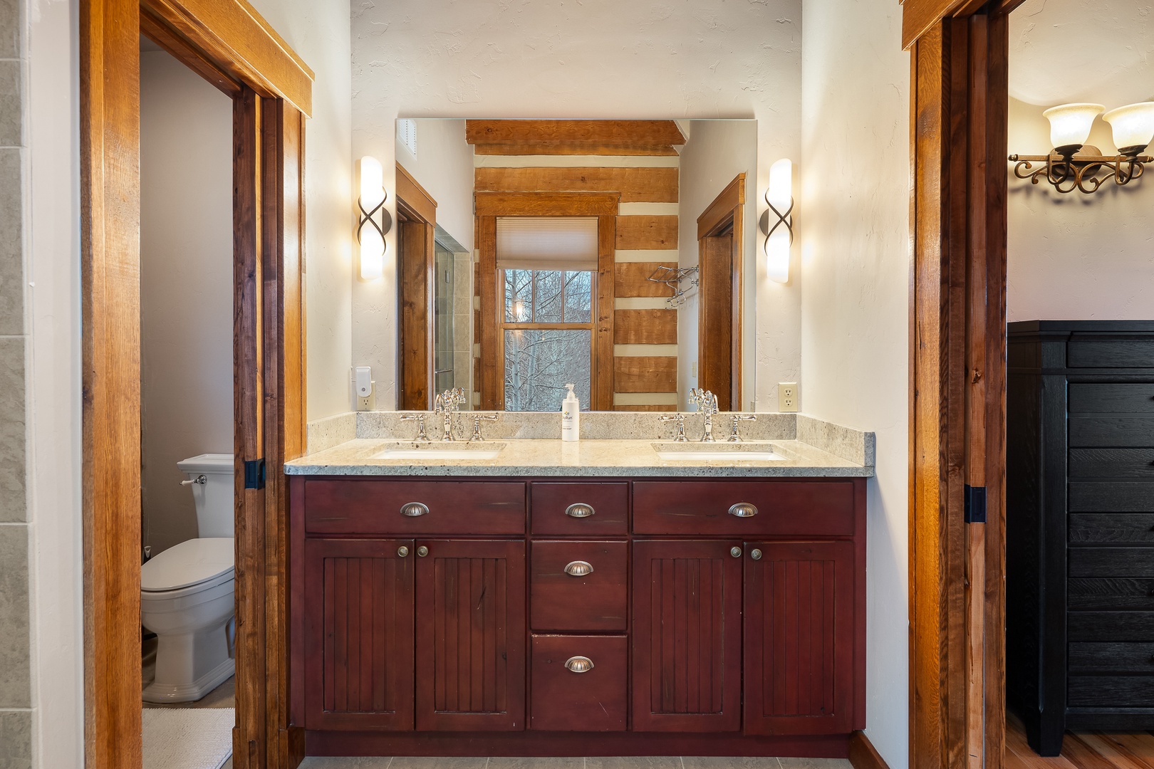 Your primary bathroom features dual sinks with granite countertops and rich wood cabinetry,
