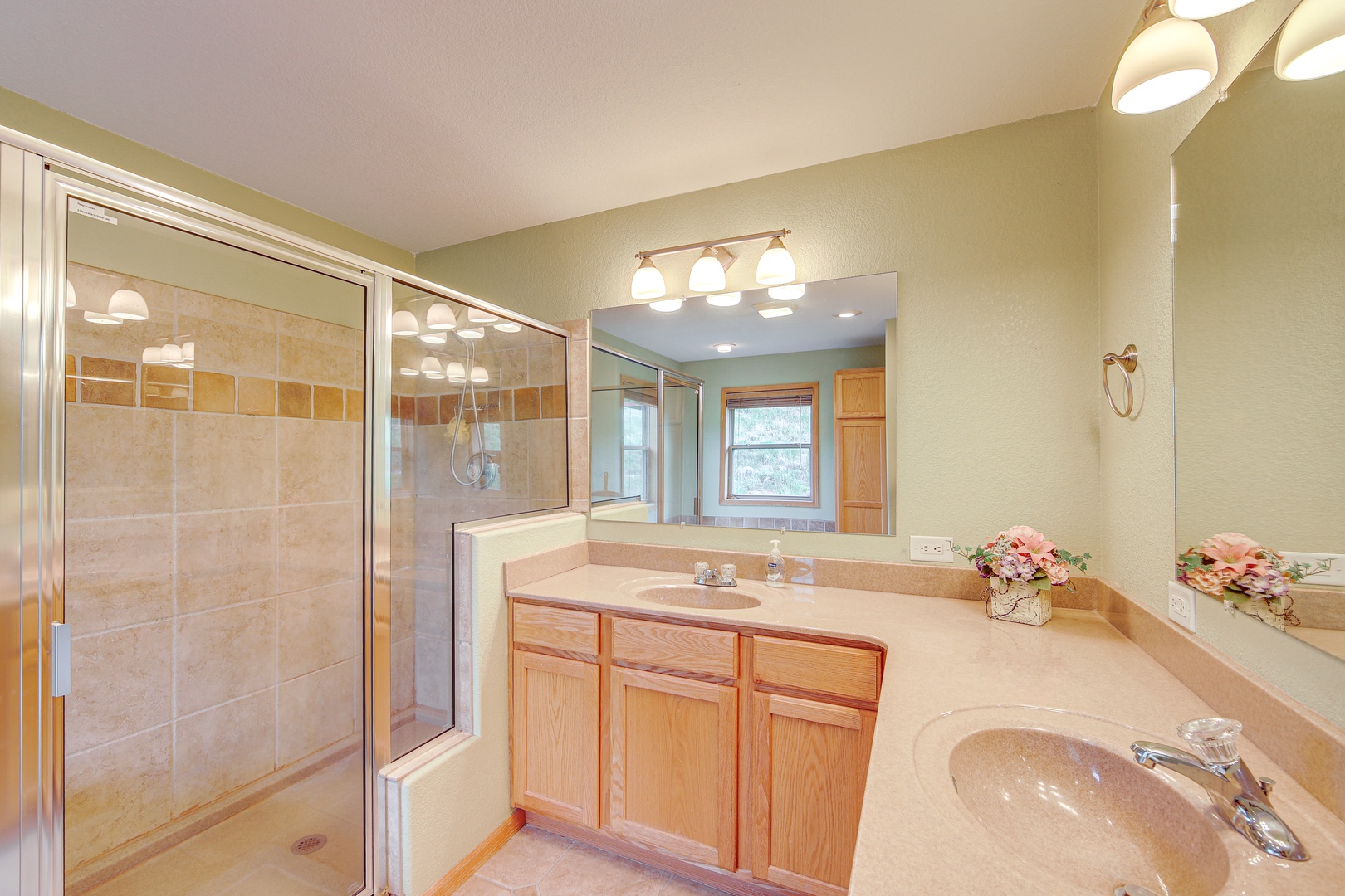 Spacious master bathroom with double sinks, large tiled shower, and warm lighting creates your perfect morning routine sanctuary.