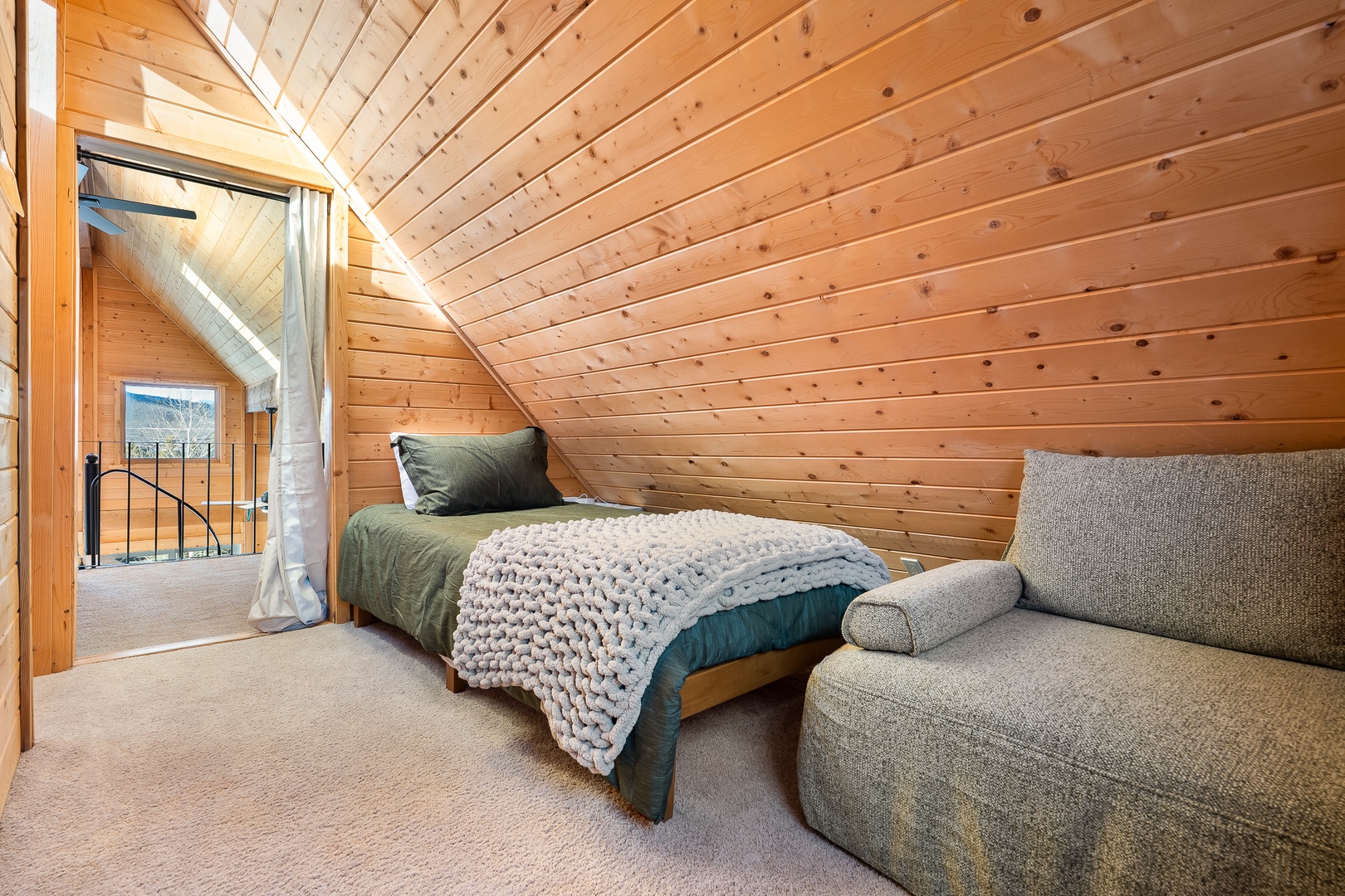 Snuggle into this charming loft bedroom where warm wood surrounds you and soft textures invite peaceful sleep under the slanted ceiling.
