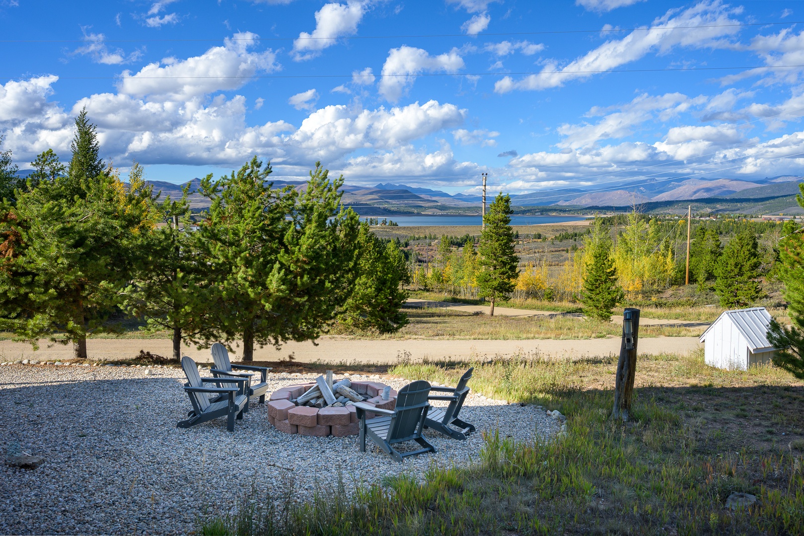 The property offers scenic mountain and lake vistas set in a natural autumn landscape, with an outdoor fire pit area perfect for crisp evening gatherings.