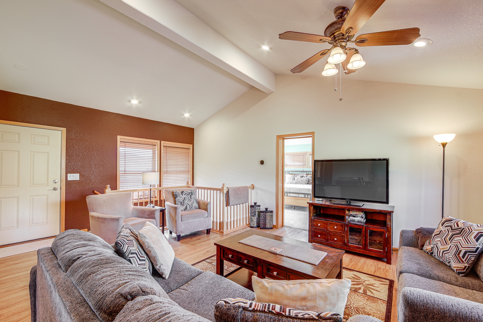 Unwind in your spacious living room with comfortable seating, warm wood accents, and entertainment center for cozy evenings together.