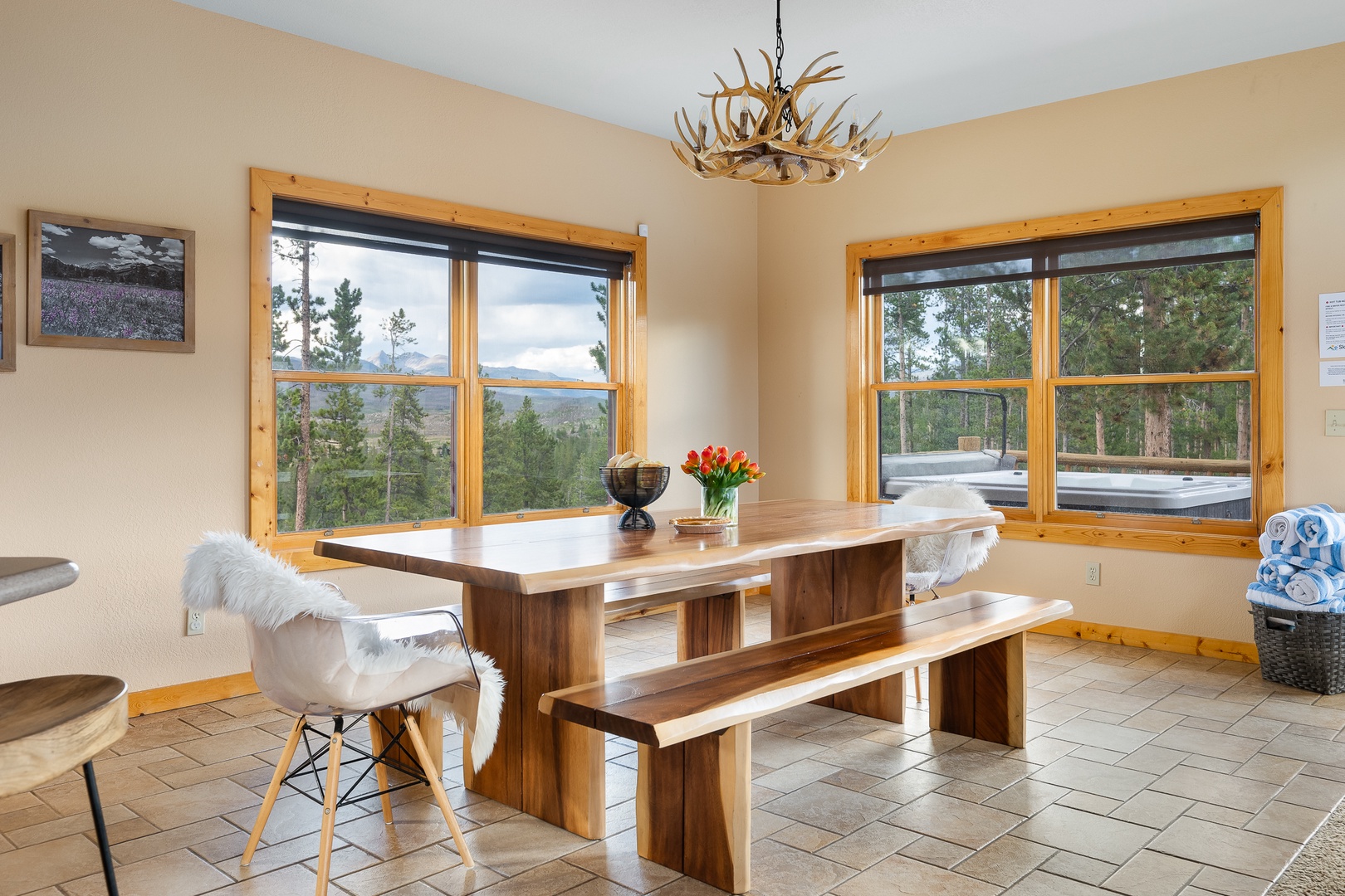 Gather around the handcrafted wooden table and let natural light pour through expansive windows framing peaceful mountain vistas—your perfect spot for morning coffee or sharing stories with loved ones.