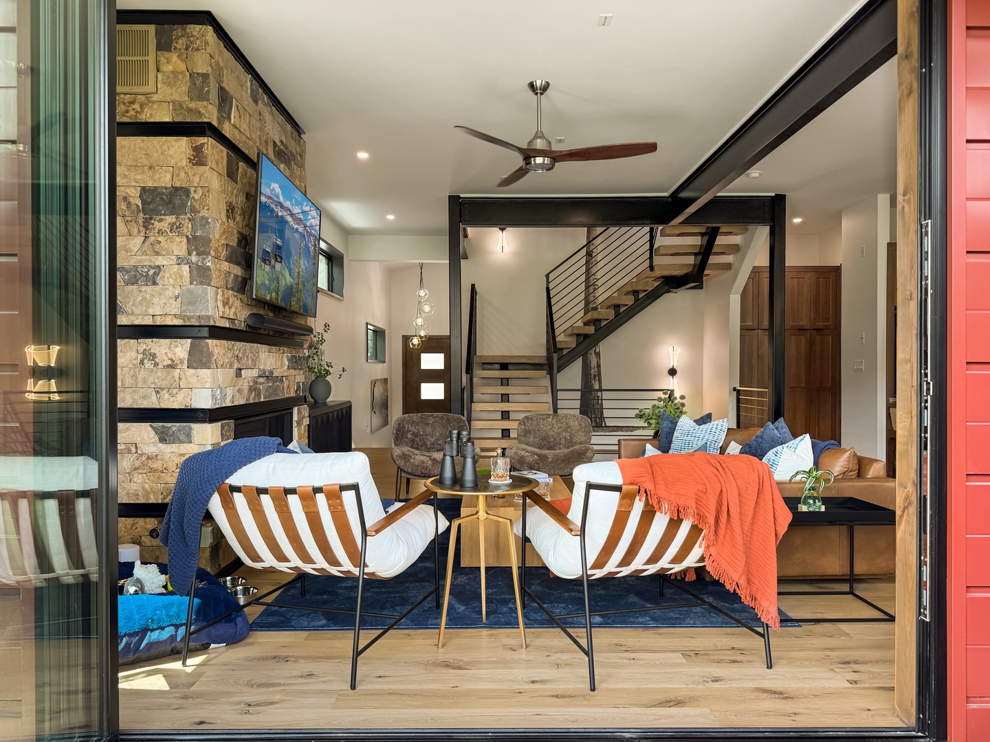 Step into your stylish open-concept retreat with soaring ceilings, a striking stone fireplace, and modern furnishings inviting you to relax and unwind in comfort.