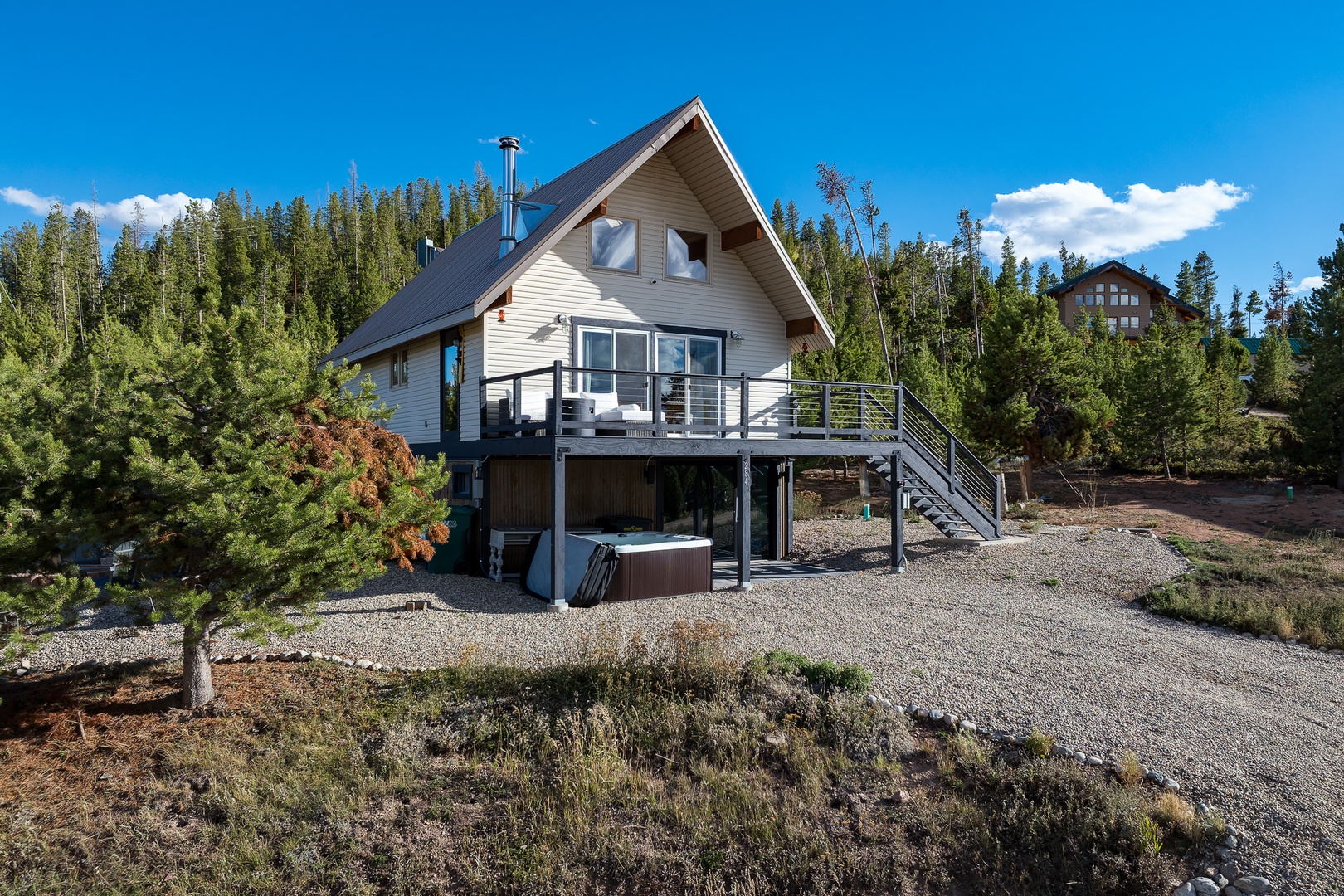 A cozy alpine retreat nestled among towering pines and aspen, featuring a private hot tub and mountain deck—your perfect escape into nature under sunny skies.