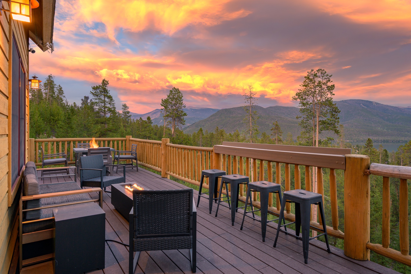 A stunning mountain sunset paints the sky in vibrant oranges and purples beyond the surrounding forest, framing the property's natural setting at arrival.