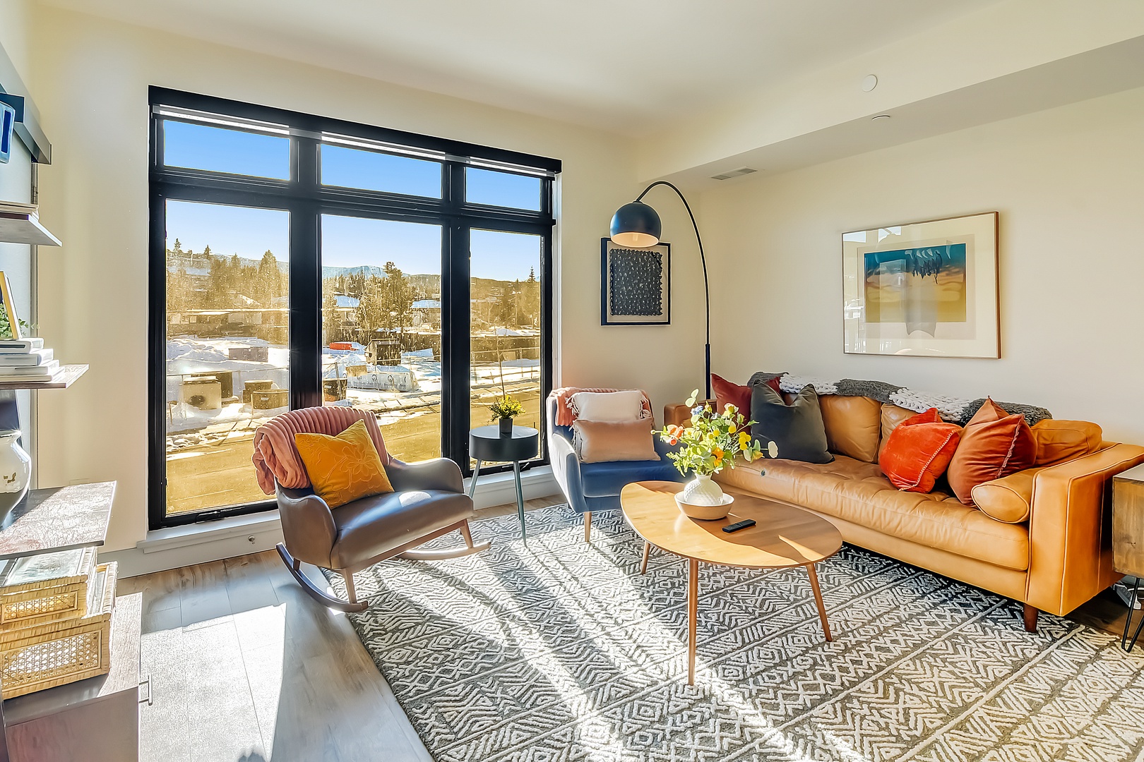 Relax in your stylish living space with vibrant orange leather sofa, modern décor, and stunning city views through floor-to-ceiling windows.