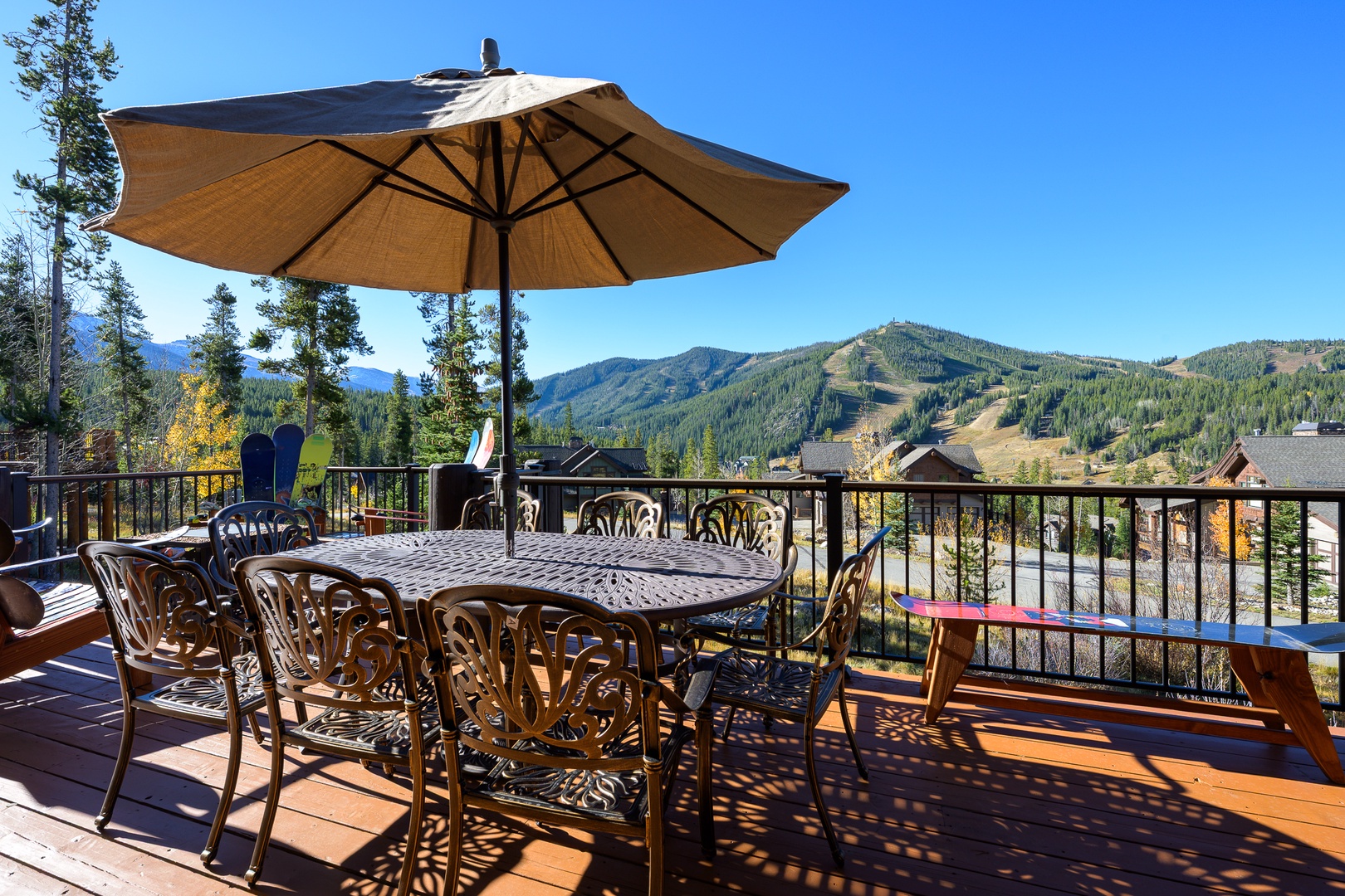 Expansive deck with mountain views features outdoor dining and umbrella shade for memorable meals.