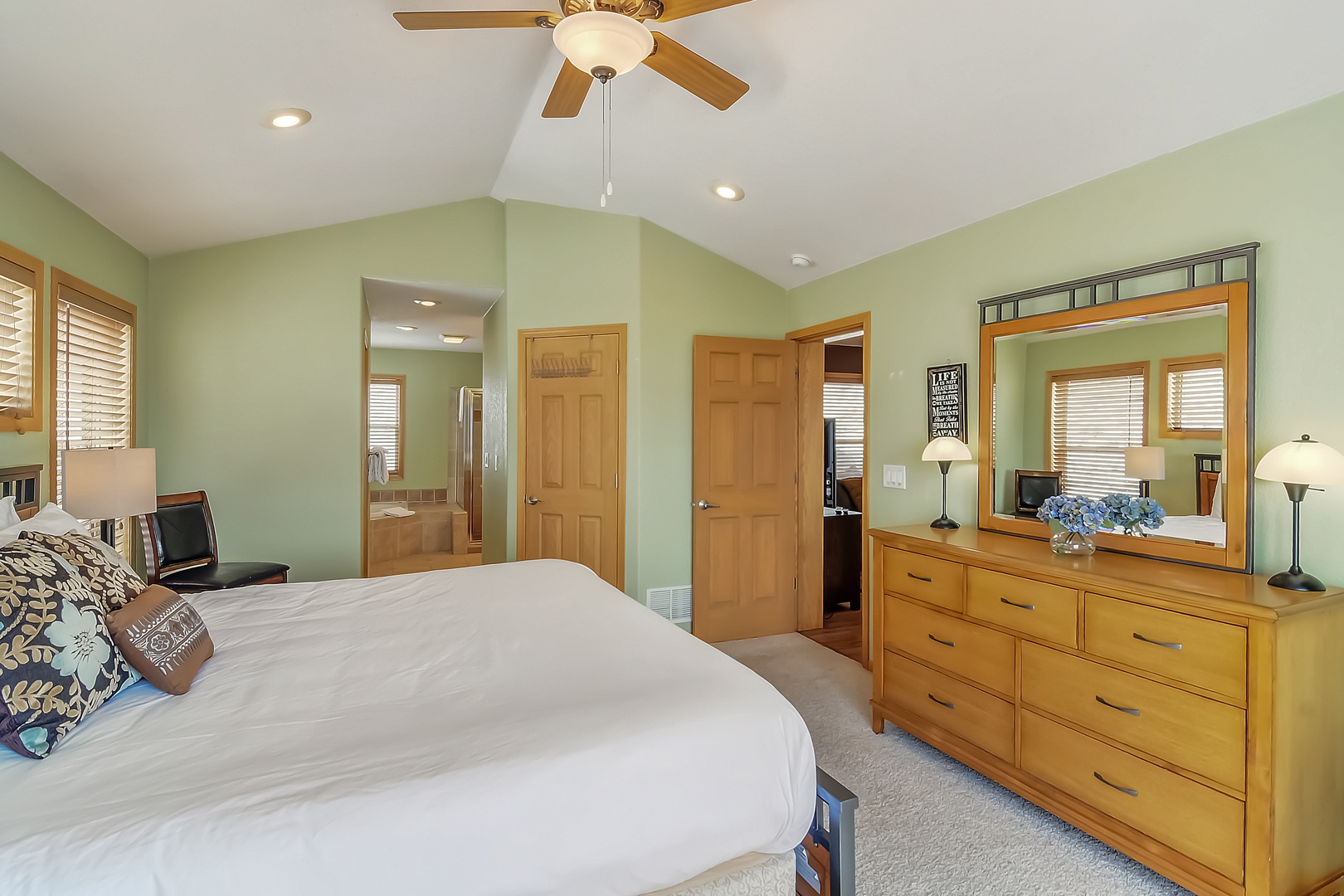 Unwind in your spacious bedroom with soothing sage walls, warm wood furnishings, and ceiling fan for perfect comfort.