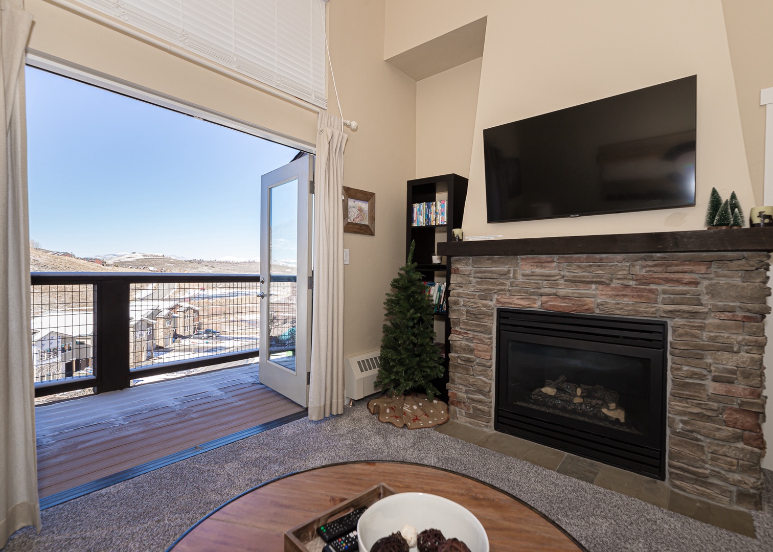 Relax in your inviting living room where a stone fireplace creates warmth while you enjoy mountain views through floor-to-ceiling windows.