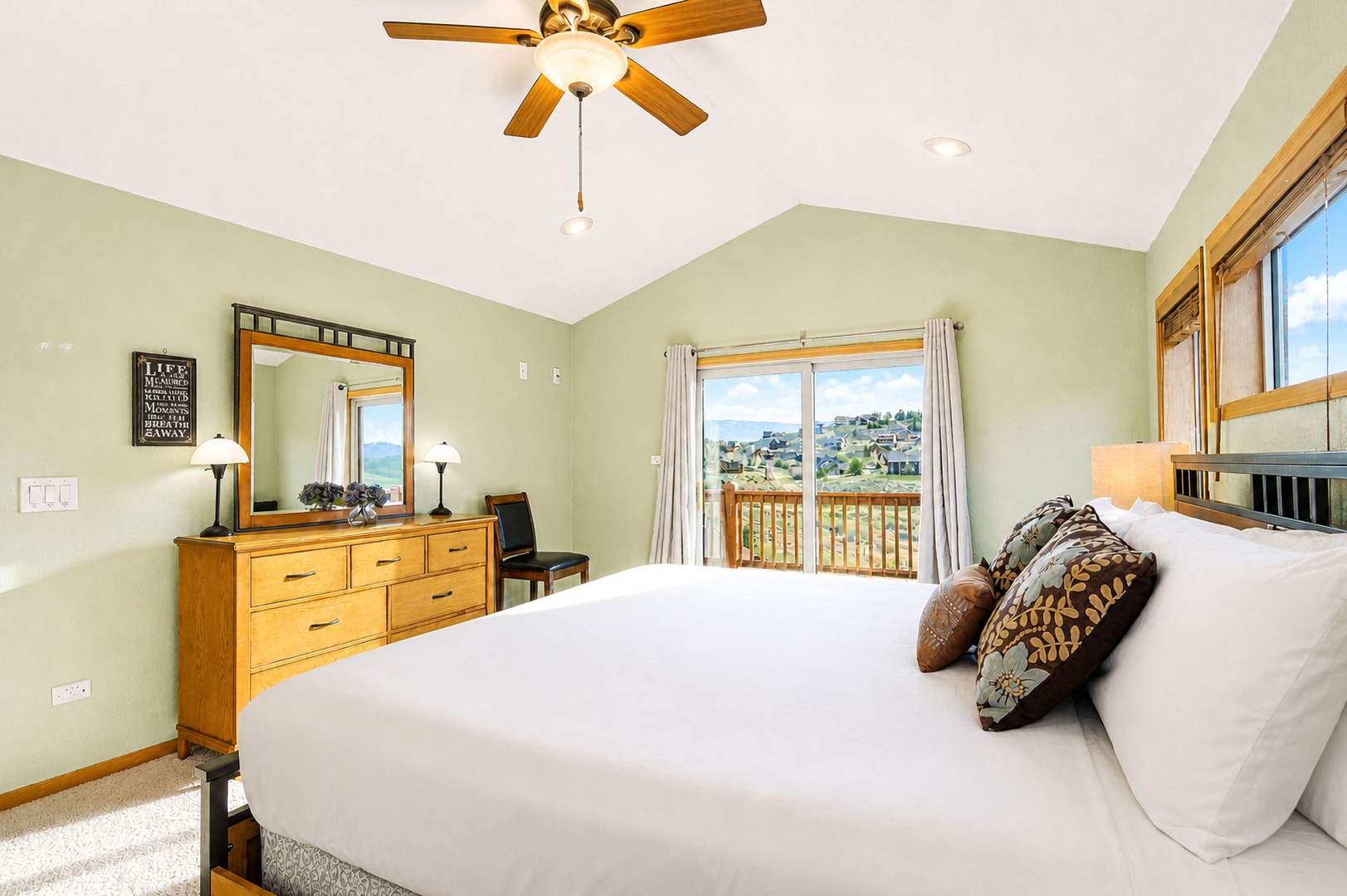 Wake up refreshed in this bright bedroom with plush bedding, warm wood accents, and stunning views of the neighborhood through sliding glass doors leading to your private balcony.
