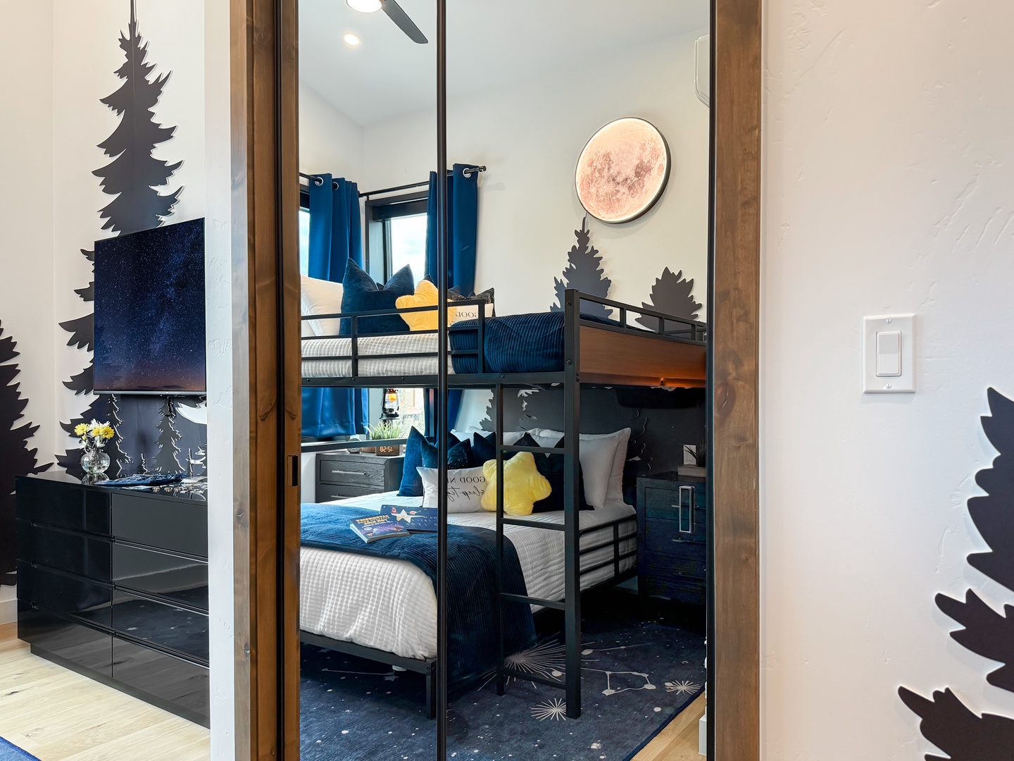 Your kids will love bunking down in this nature-themed bedroom, complete with playful pine tree decor and cozy blue bedding that sets the stage for mountain adventure dreams.